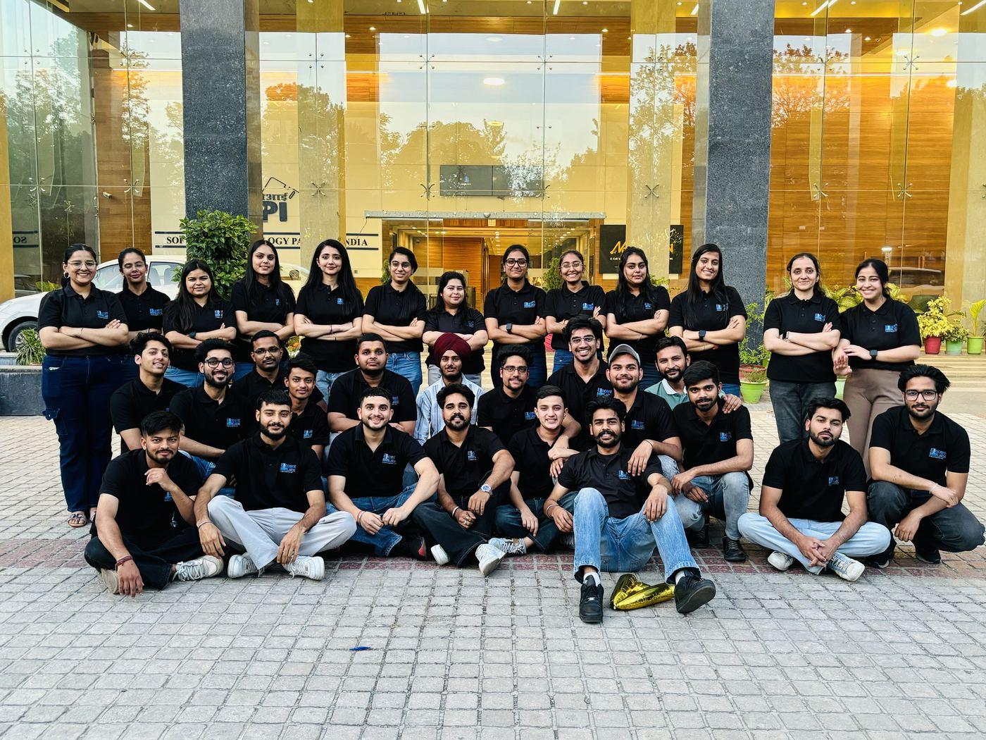 The full team in branded shirts outside the office on foundation day